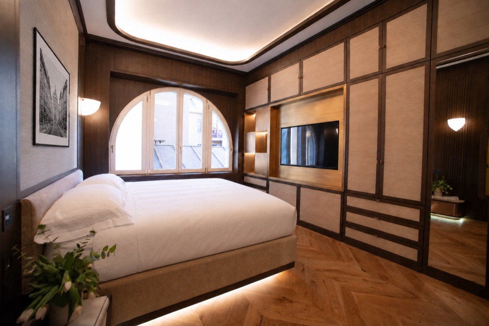 Second king bedroom with a king bed and a large arched window over the Milan rooftops